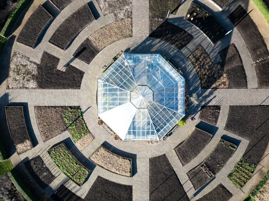 Aerial view of a circular architectural structure with a glass dome centerpiece surrounded by geometric concrete sections.
