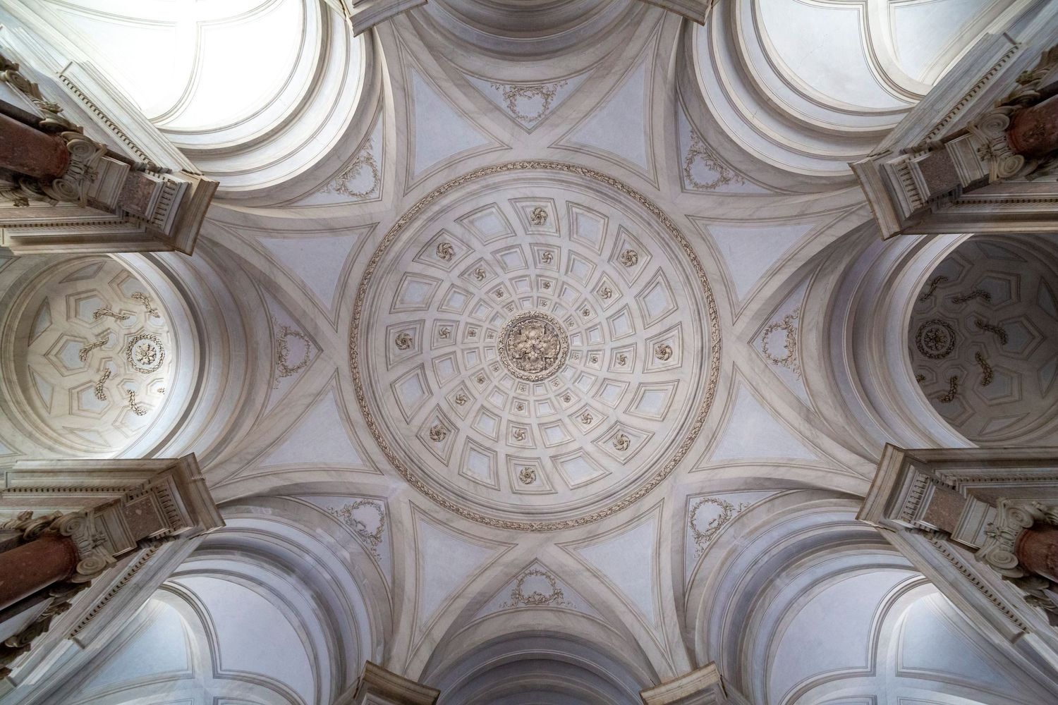 Architectural interior photography of Baroque church ceiling featuring ornate plasterwork, dome and historic detailing.