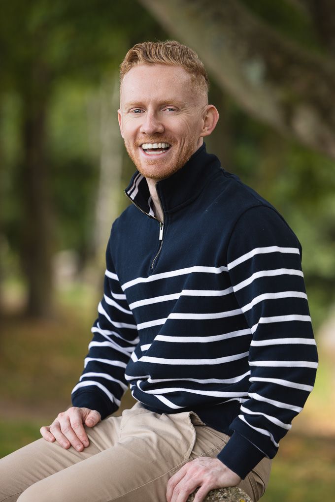 Person wearing a navy and white striped sweater sits outdoors with a warm smile.