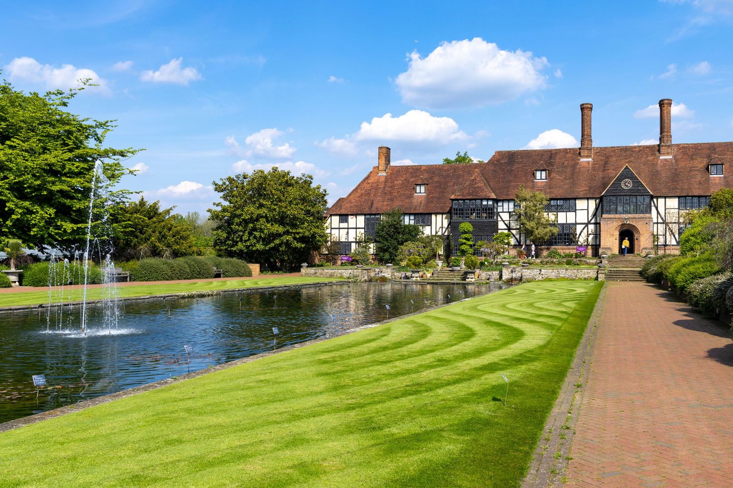 Tudor-style manor house with formal gardens, fountain pond and landscaped grounds.