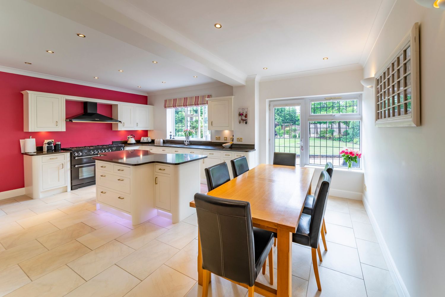 Modern open-plan kitchen diner with bespoke cabinetry, dining area and garden views for property photography.