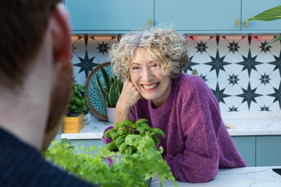 A lifestyle shoot in London of a person smiling while tending to fresh green plants in a garden setting.