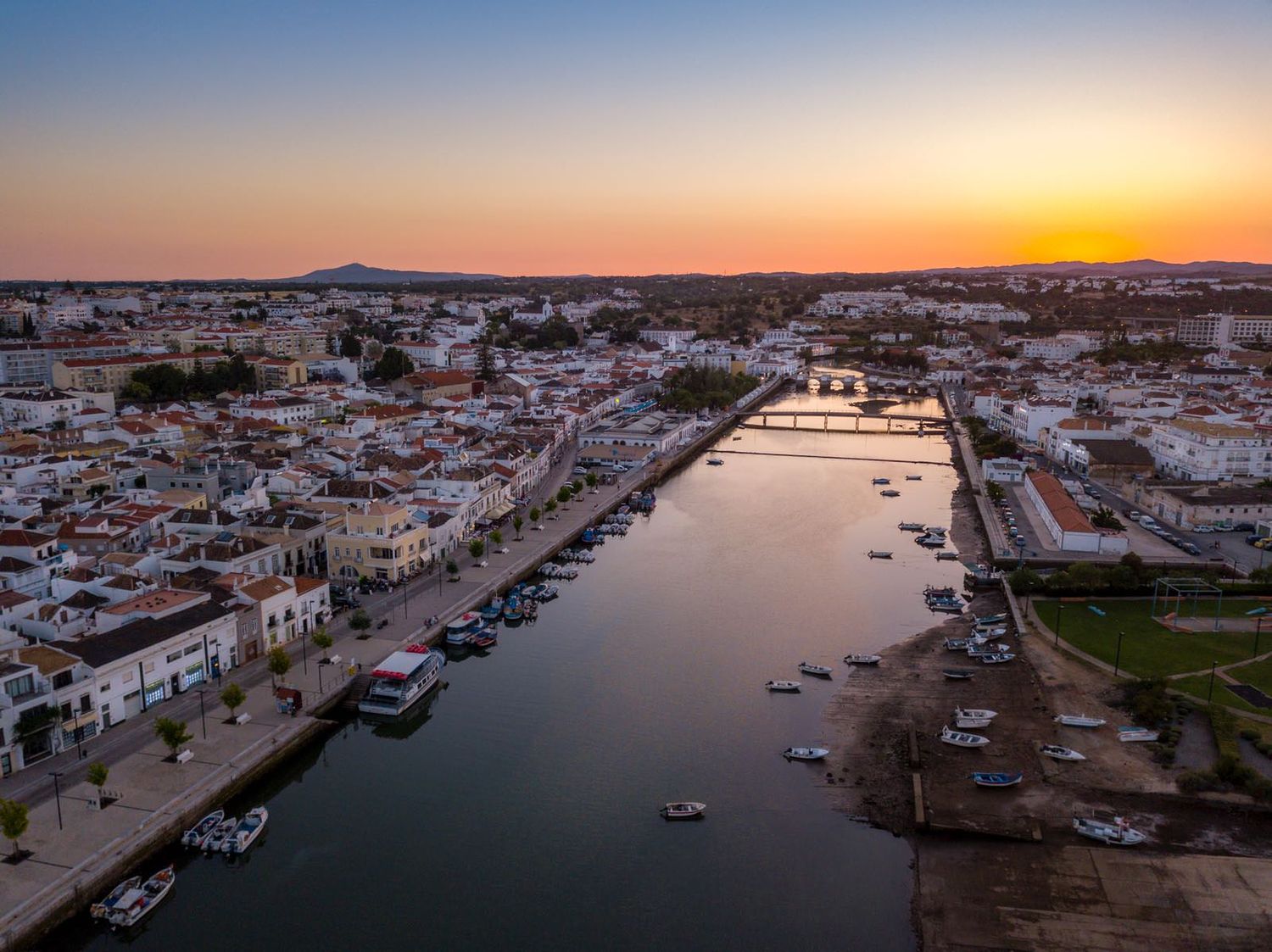 Aerial sunset view of Tavira, Portugal, with the Gilao River reflecting golden hues through the historic town.