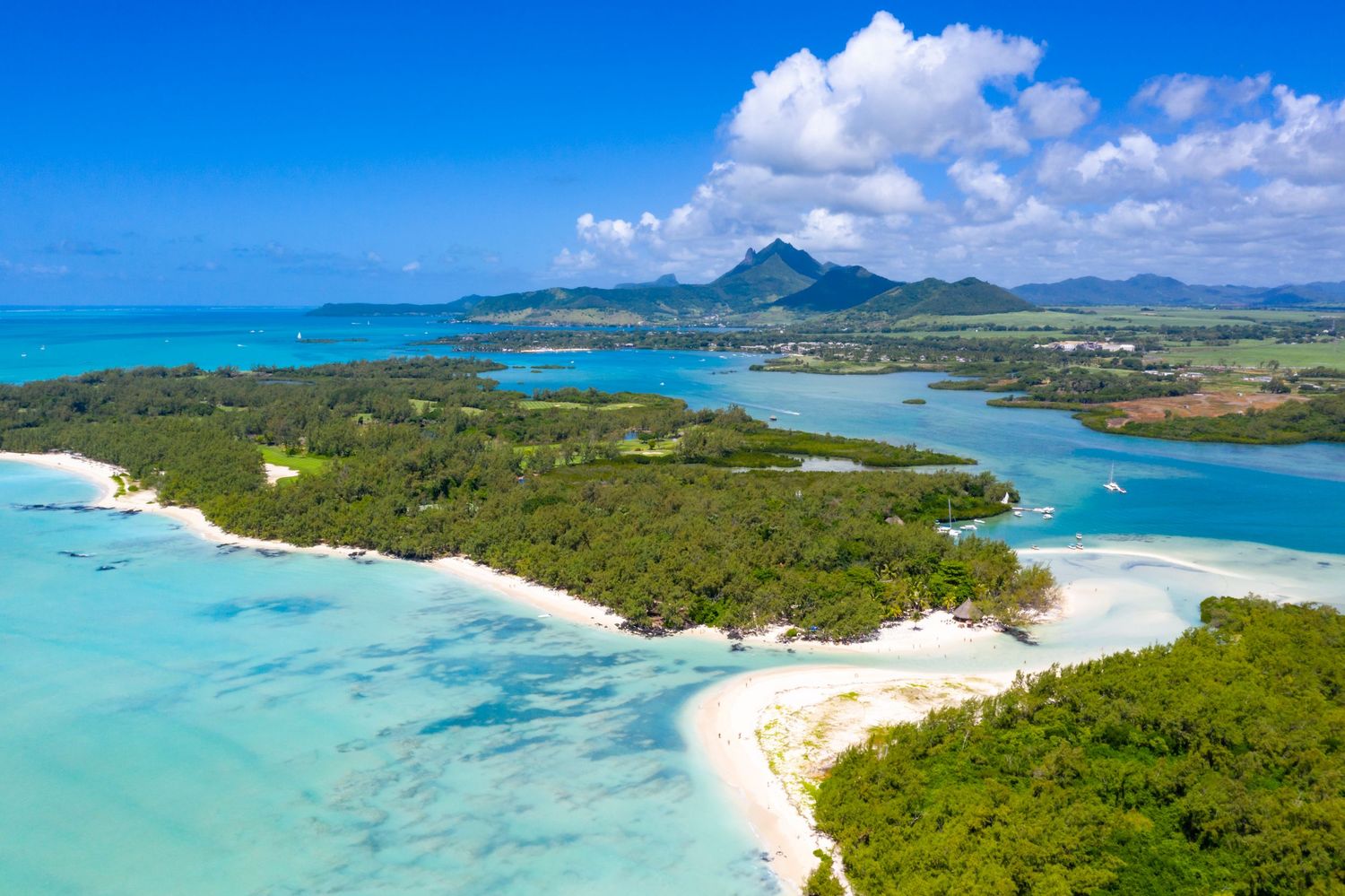 Aerial drone photograph of a tropical island featuring white sandy beaches, turquoise waters and lush coastal vegetation.