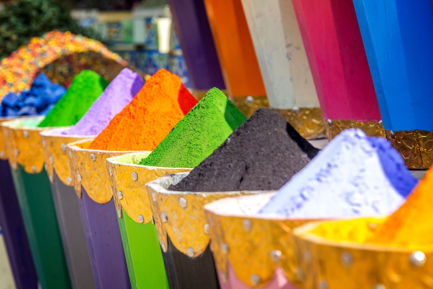 Vibrant colorful powder pigments displayed in rows at an outdoor market, perfect for Holi festival celebrations.