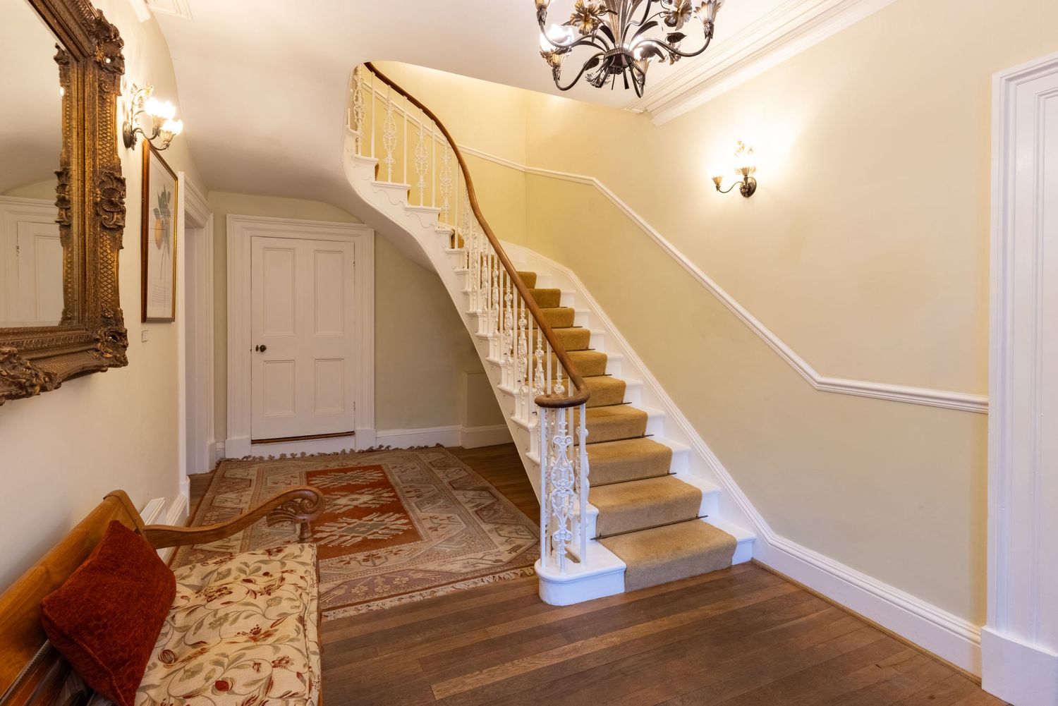 Traditional home entrance hall with sweeping staircase, hardwood flooring and elegant period interior design.