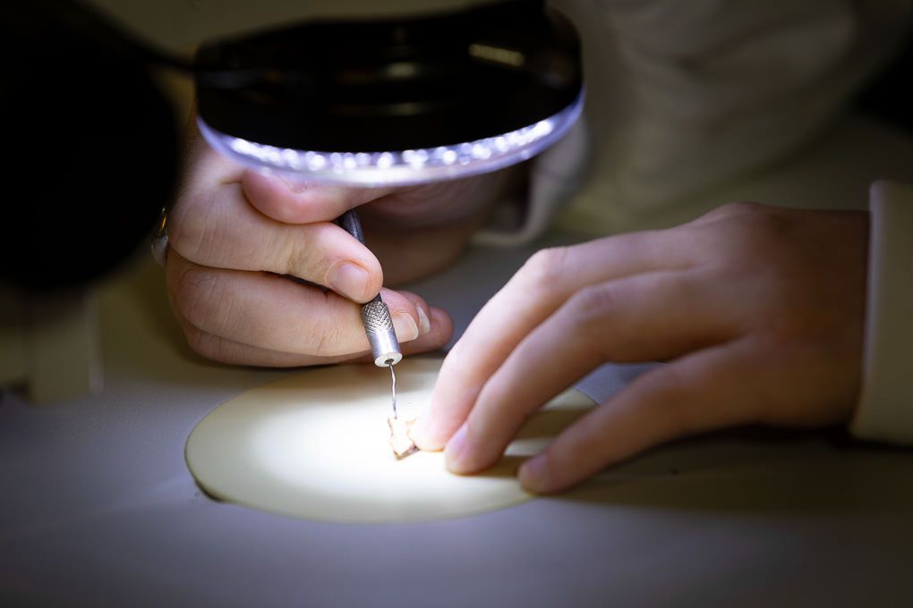 Close-up sequence of hands sewing white fabric with thread and needle in dim lighting.