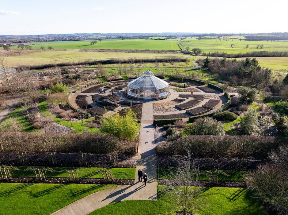 Panoramic aerial views of an agricultural landscape with curved green terraces and scattered buildings on a sunny day.