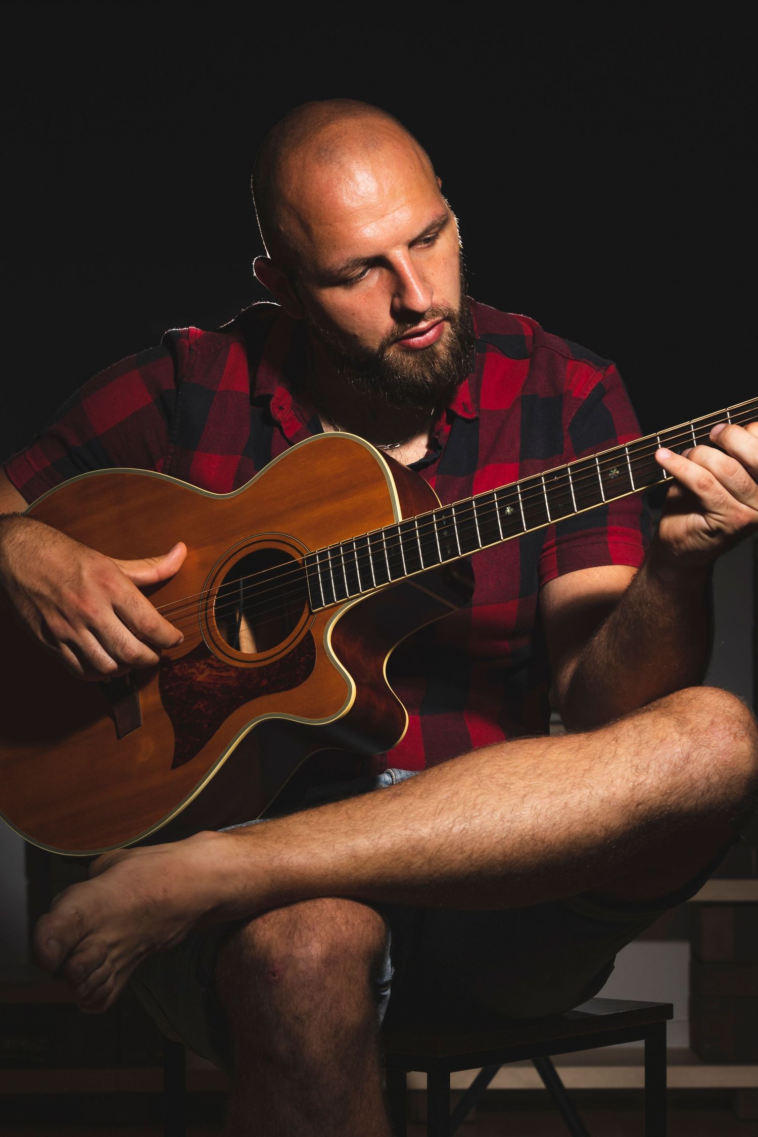 Portrait of musician playing acoustic guitar against a dark background during a professional personal branding photography session.