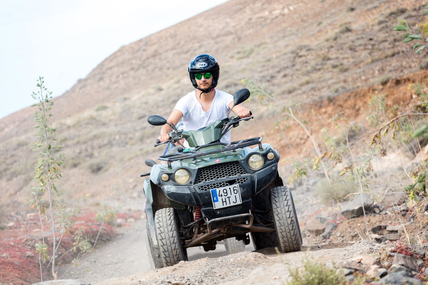 A rider enjoying an ATV adventure in rugged mountainous terrain on a sunny day.