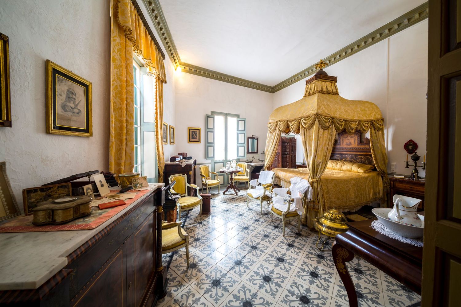 Luxury bedroom interior in historic European villa featuring antique furnishings, ornate flooring and period design details.