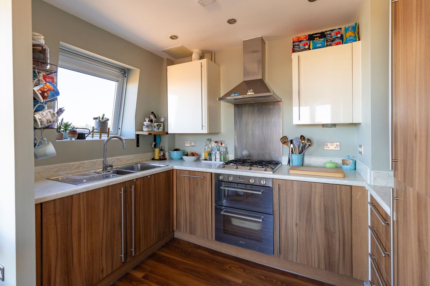 Modern kitchen with wood-effect cabinets, stainless steel extractor, gas hob, double oven, and granite worktops.
