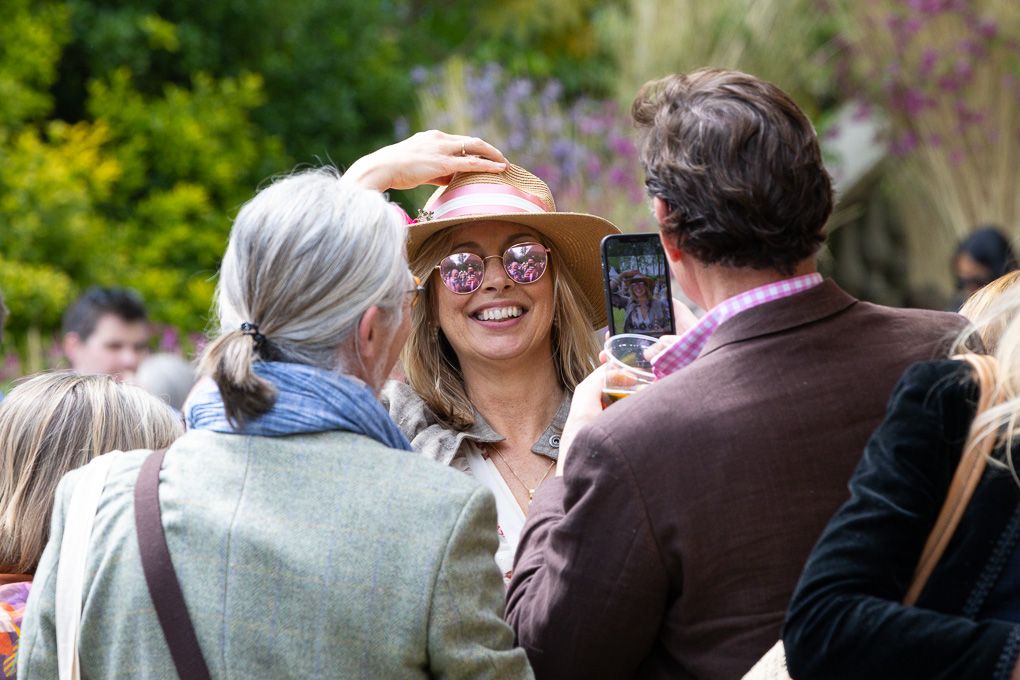 People gather outdoors at a social event on a sunny day at the RHS Chelsea Flower Show.