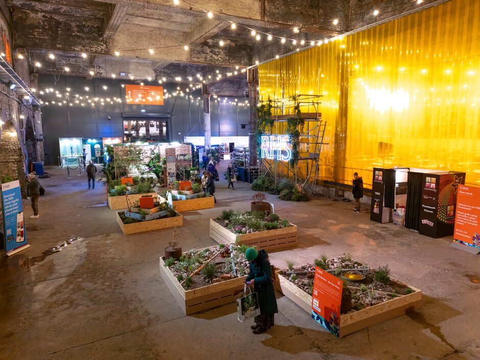 Indoor urban garden space with string lights, wooden planters, and industrial decor in a converted warehouse setting.