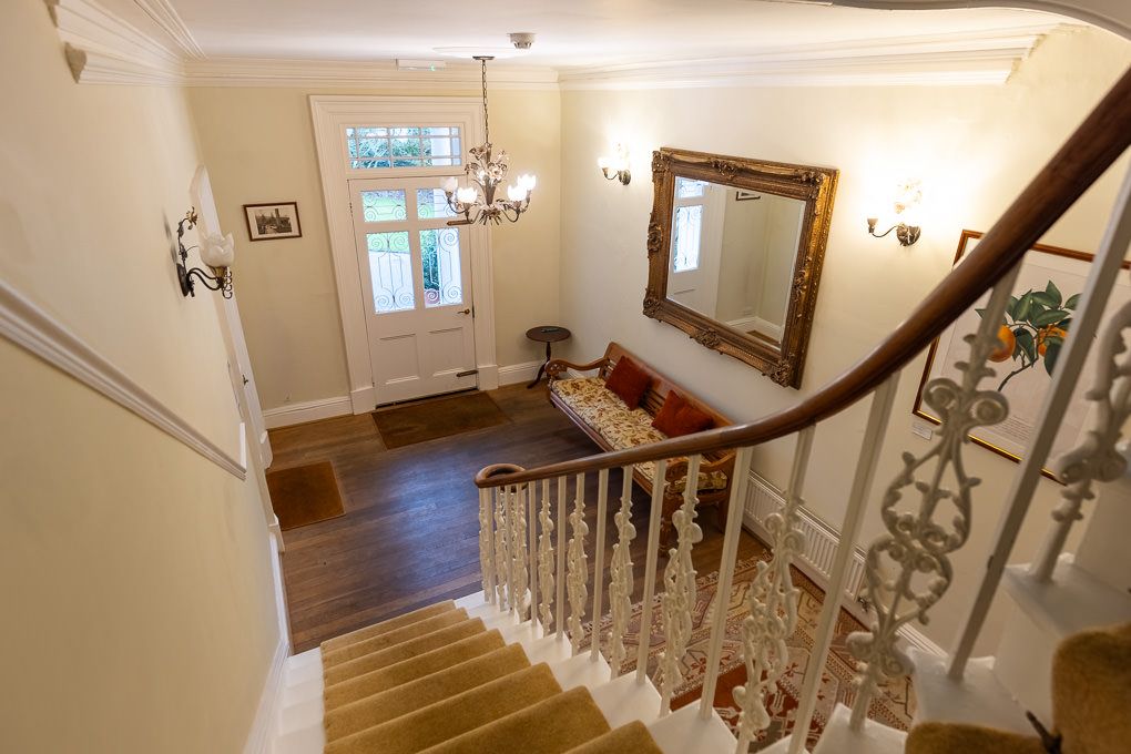 Elegant hardwood staircase with ornate railings in bright residential hallway - property interior photography showcasing layout