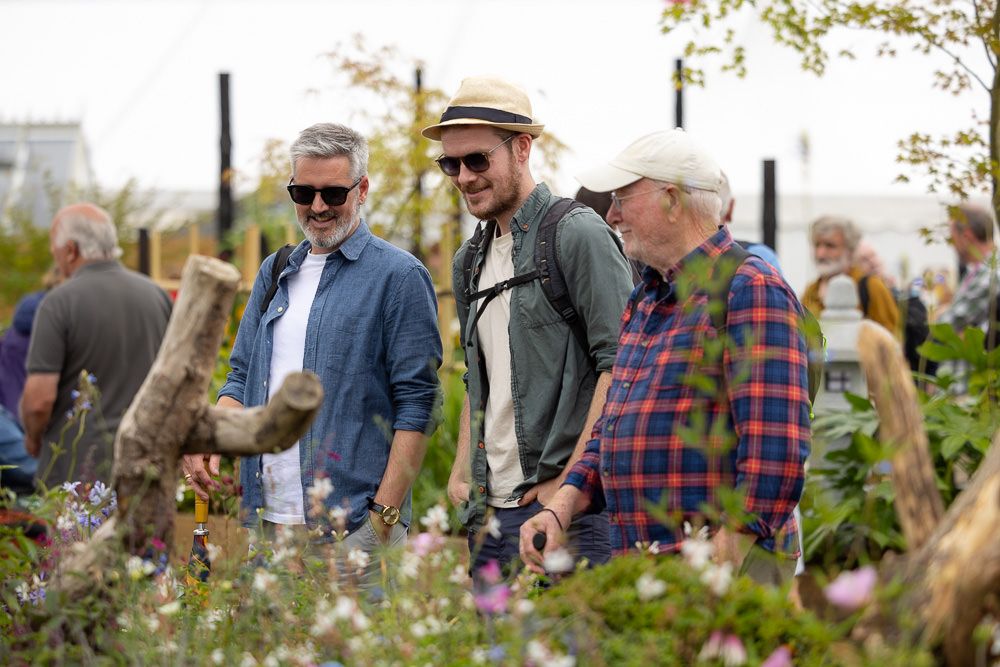 Group of people gathered outdoors for a social event under flowering trees.