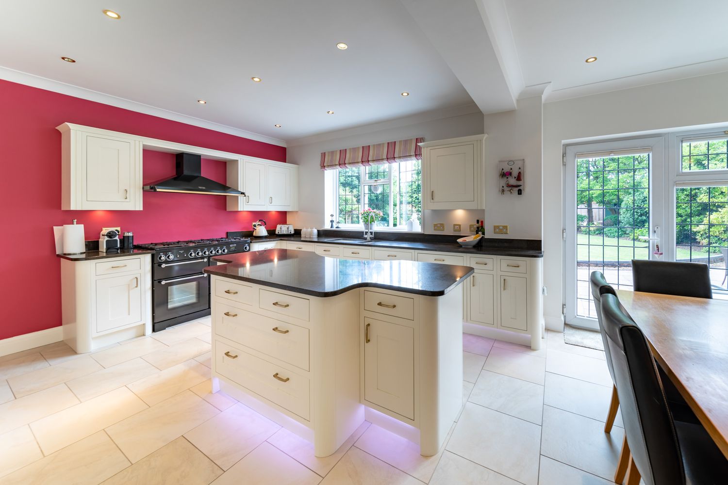 Photograph for an estate agent of a modern kitchen with purple LED lighting, dark sectional couch, and floor-to-ceiling windows.