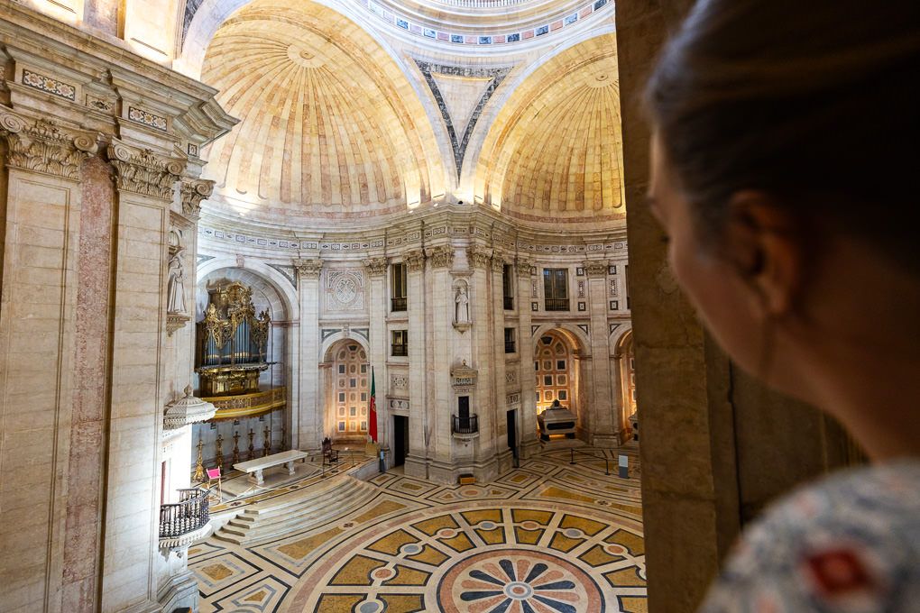Interior view of Saint Peter's Basilica in Vatican City showing ornate marble floors and gilded domed ceiling.