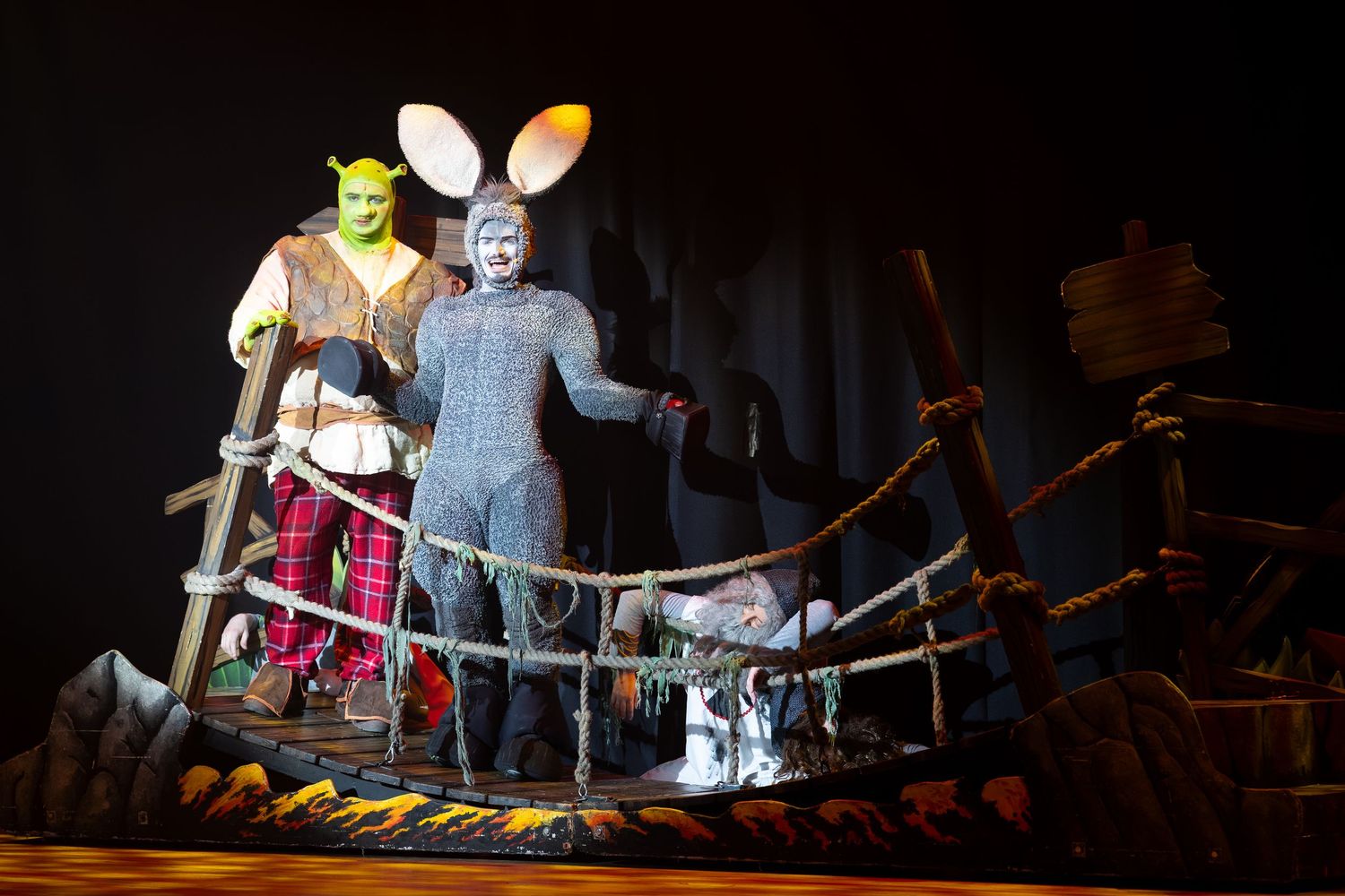 Shrek and Donkey on a wooden bridge set during Shrek The Musical at Castle Theatre Wellingborough