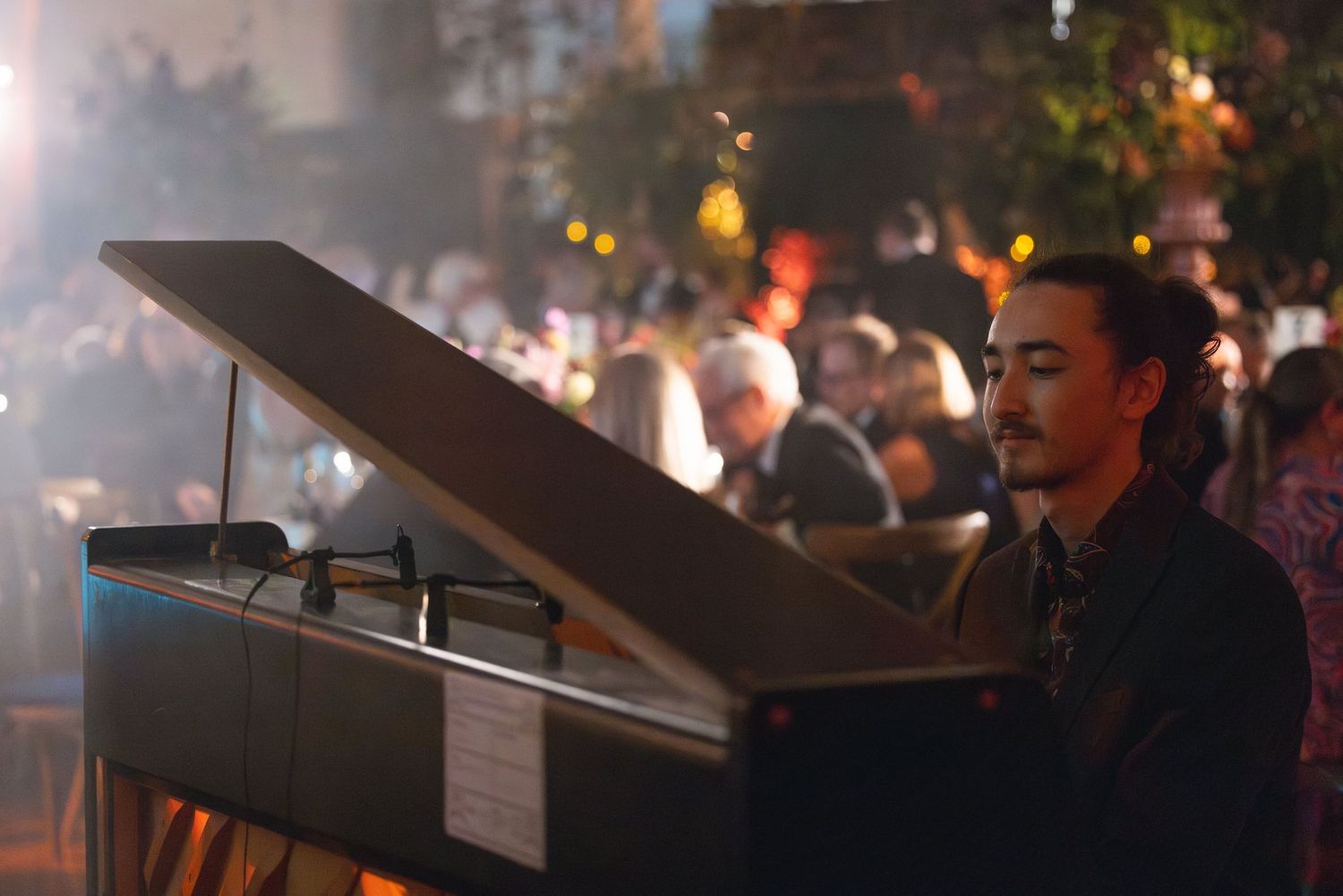 Pianist performing at an outdoor corporate event as guests enjoy an evening reception