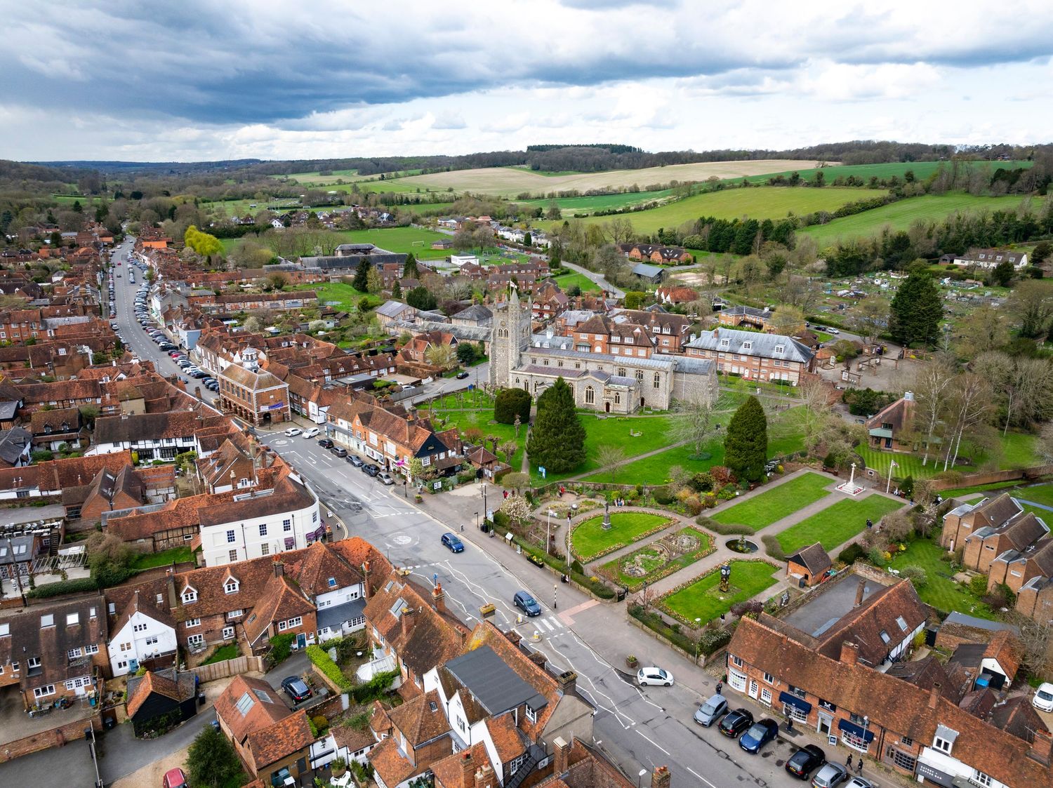 Aerial drone photograph of a traditional English village featuring historic buildings, a parish church and surrounding countryside.