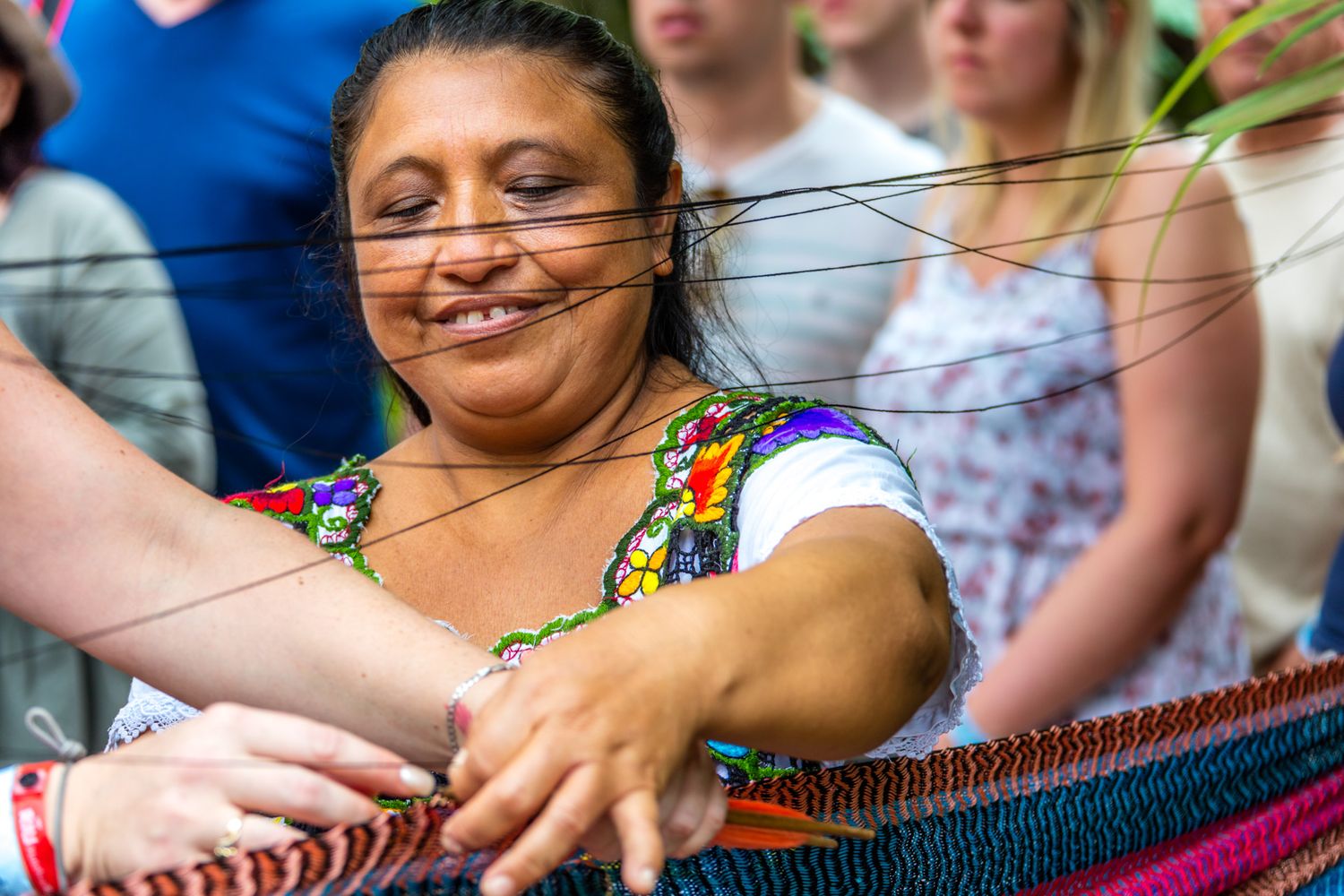 Person in colorful dress enjoying a festive outdoor gathering with crowd behind.