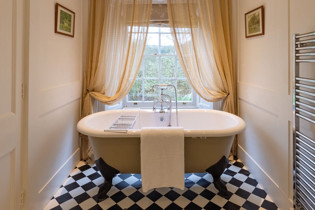 Elegant bathroom with clawfoot bath and checkered floor tiles in holiday apartment - interior photography capturing style