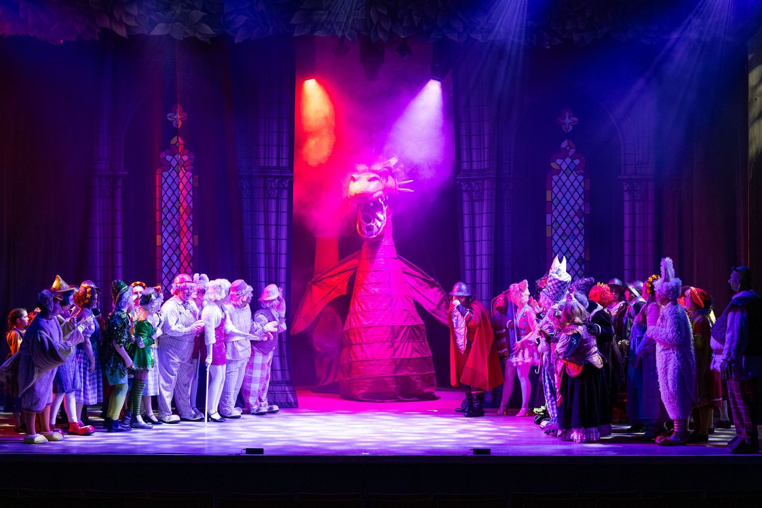 Dragon scene with large cast in Shrek The Musical under dramatic lighting at Castle Theatre Wellingborough