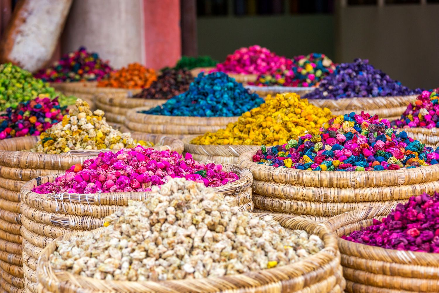 Colorful dried flowers and herbs displayed in woven baskets at a market.