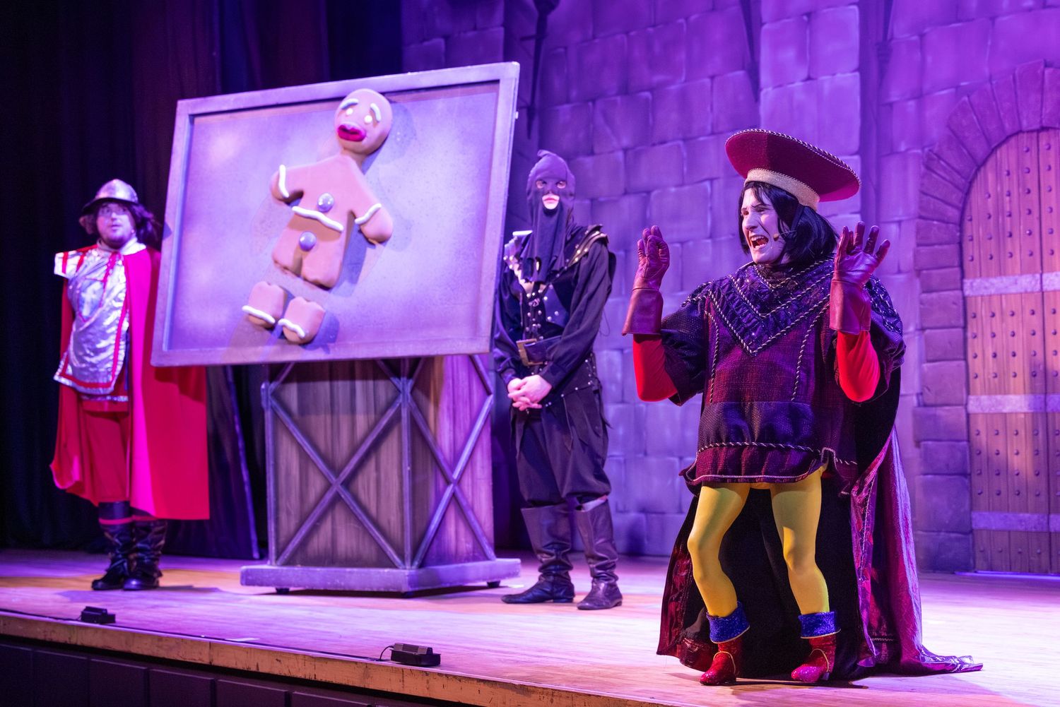 Actors perform a villain scene with the Gingerbread Man during Shrek The Musical at Castle Theatre Wellingborough