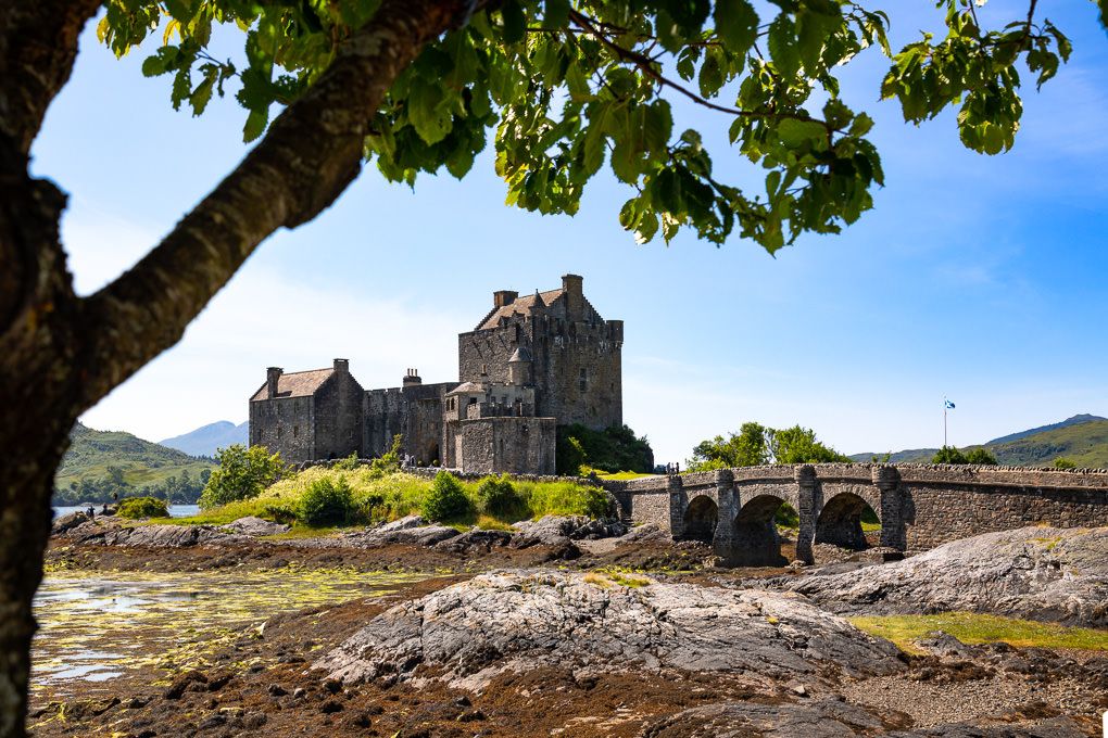 Historic stone castle Eilean Donan sits on a small tidal island in the Scottish Highlands under cloudy skies.