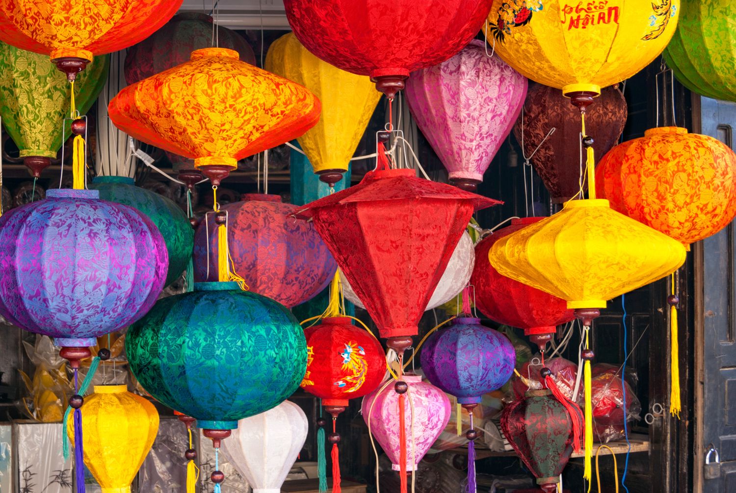 Colorful traditional Vietnamese silk lanterns in orange, red, yellow, pink, and teal hanging at a market in Hoi An.