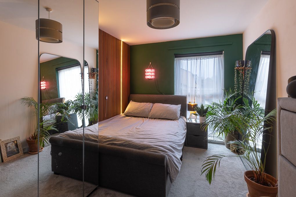 Interior photography of a bedroom with wood panelling, grey bedding, and potted plants, creating a cosy atmosphere.