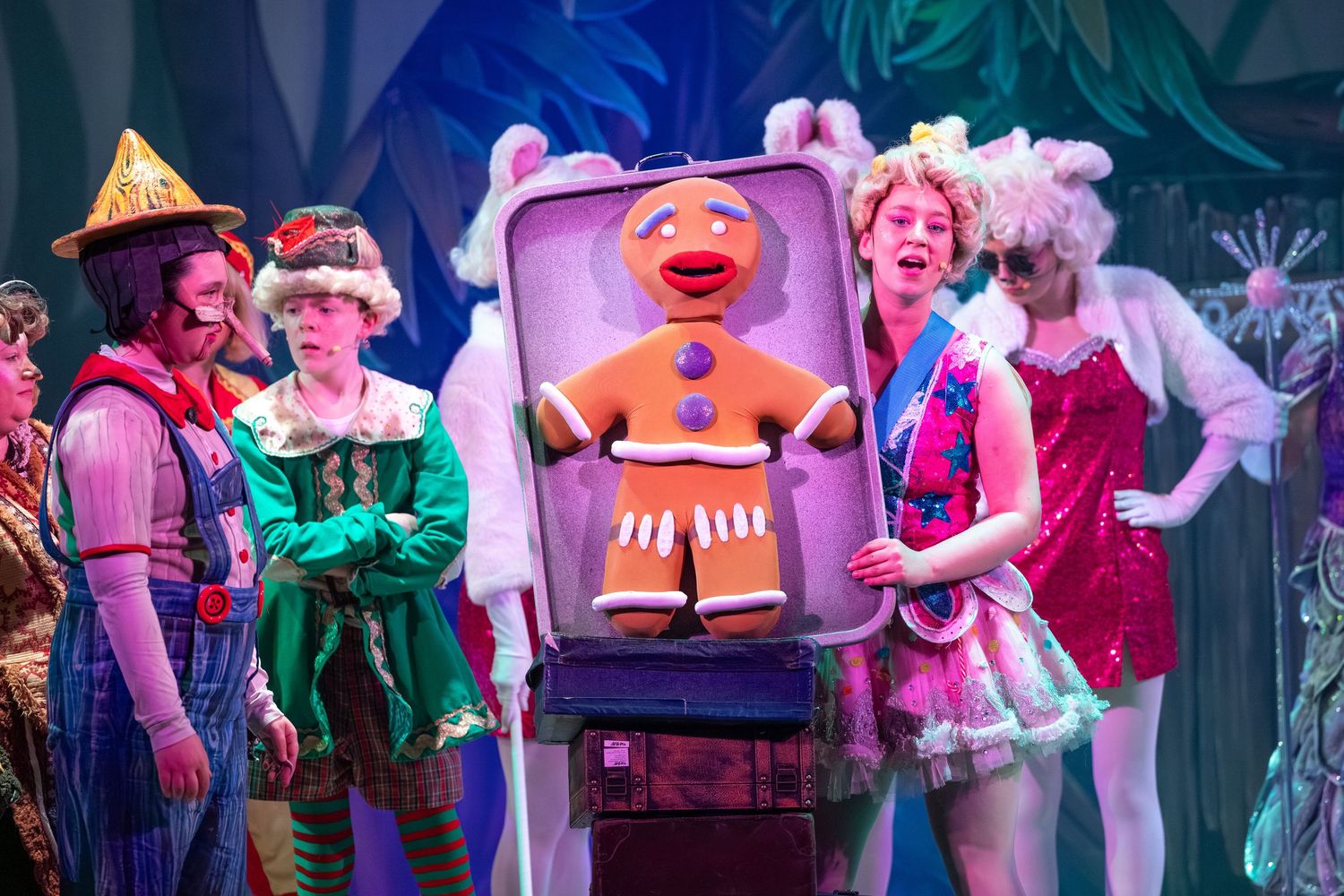 Giant Gingerbread Man prop with colourful cast in a magical stage scene from Shrek The Musical at Castle Theatre Wellingborough