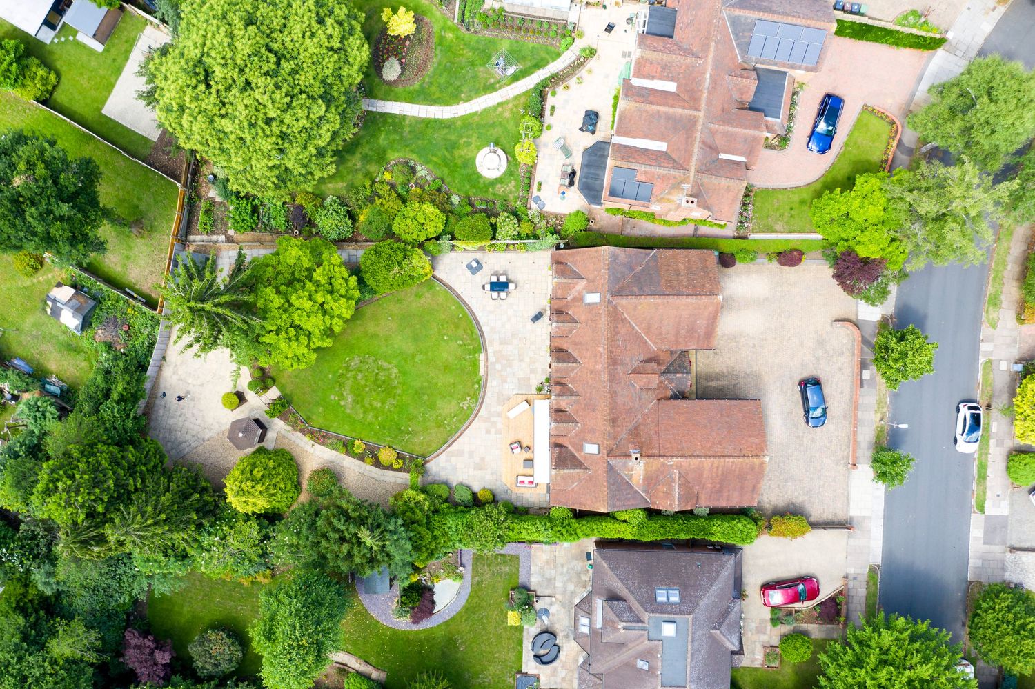 Aerial property photography of luxury family home with landscaped gardens and private tree-lined driveway.