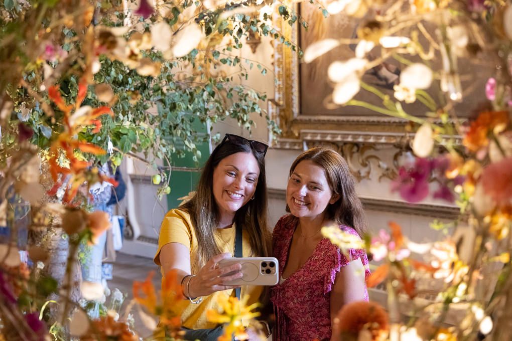 Two friends share a joyful moment together surrounded by colorful hanging paper butterflies and decorative elements.