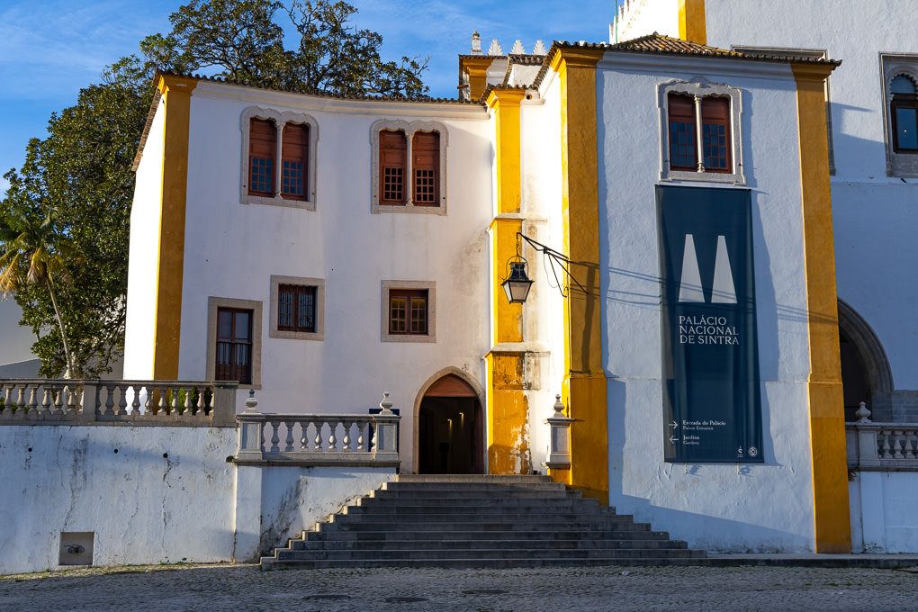 View of Portuguese colonial architecture with white walls, yellow trim, and a blue door in Évora, Portugal.