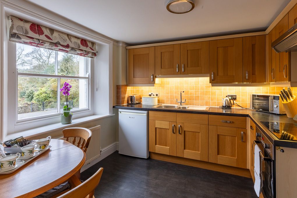 Cozy wood-panelled kitchen with built-in storage and natural light in holiday apartment - interior photography showcasing features