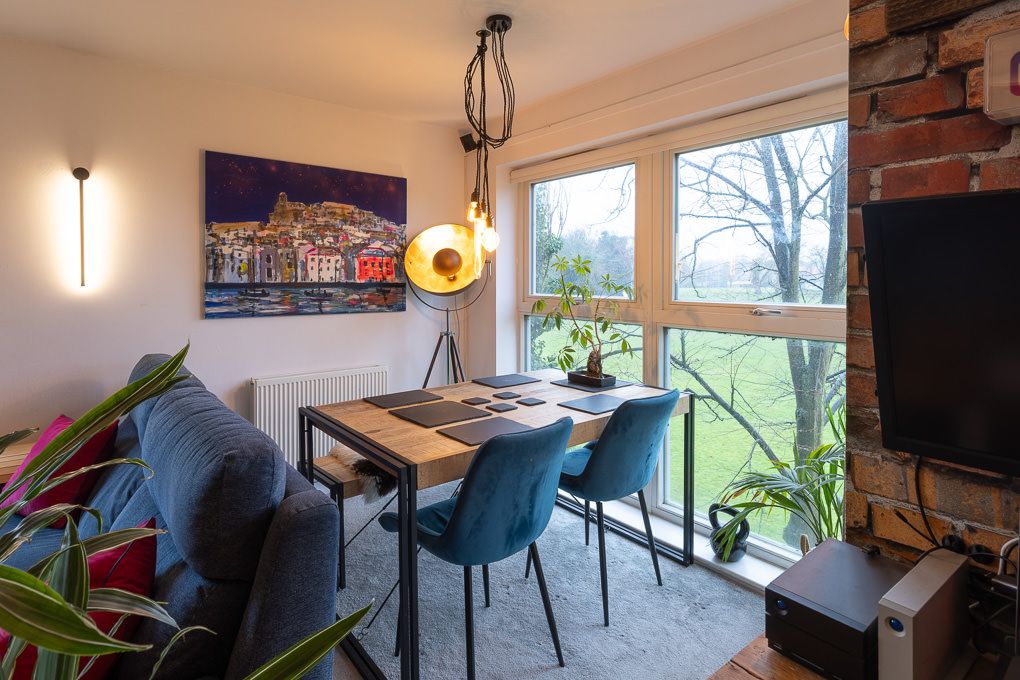 Interior photograph of an apartment interior showcasing open floor plan with exposed brick wall, contemporary furnishings and large windows.