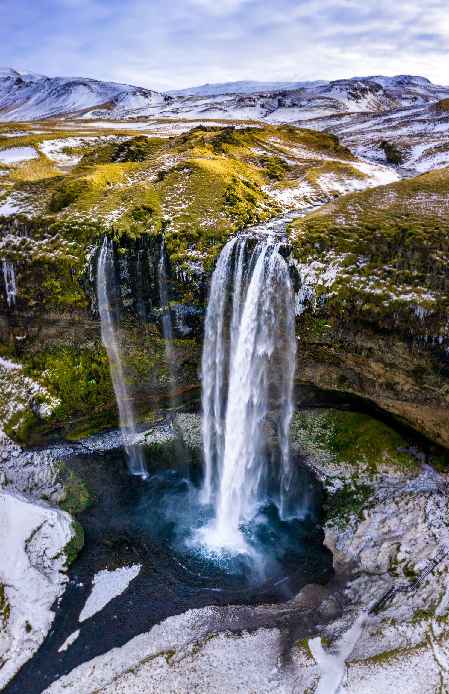 Aerial view of Seljalandsfoss waterfall in Iceland surrounded by snow-covered landscape, photographed for travel and tourism marketing.