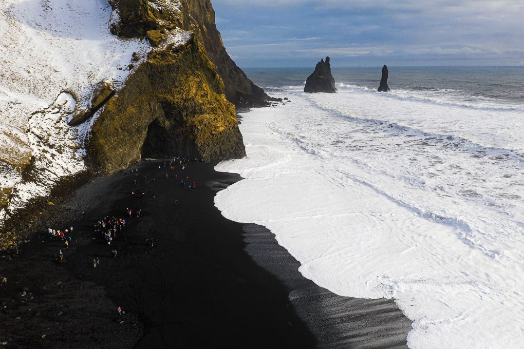 An aerial view of Reynisfjara Black Sand Beach and the rugged landscape around it.