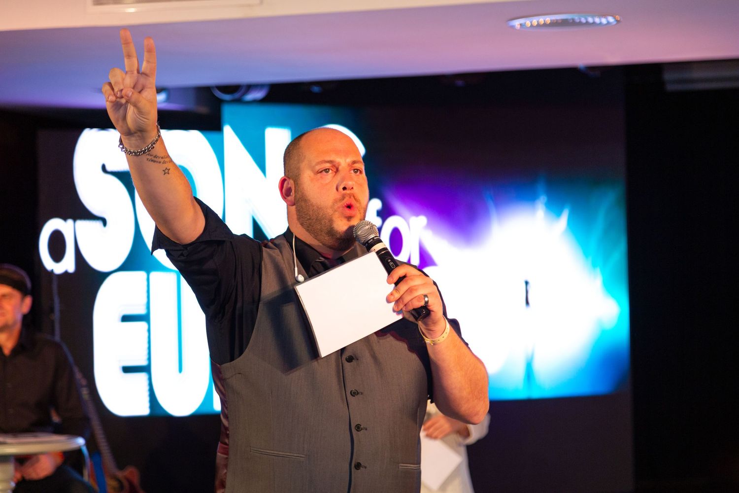 Speaker addressing an audience during a corporate event presentation with illuminated stage backdrop