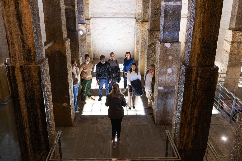 People walking up old stone steps inside a historic building entrance with ornate columns.