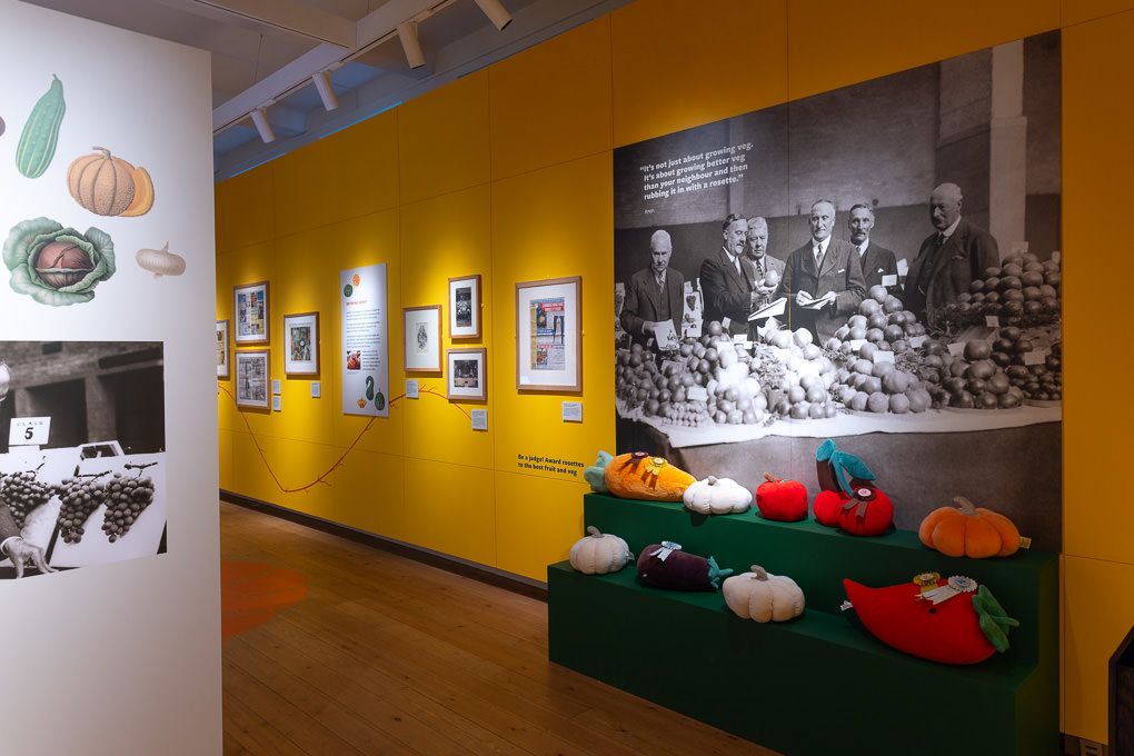 RHS Pumpkins and Prizes exhibit gallery with yellow walls displaying historical photographs.