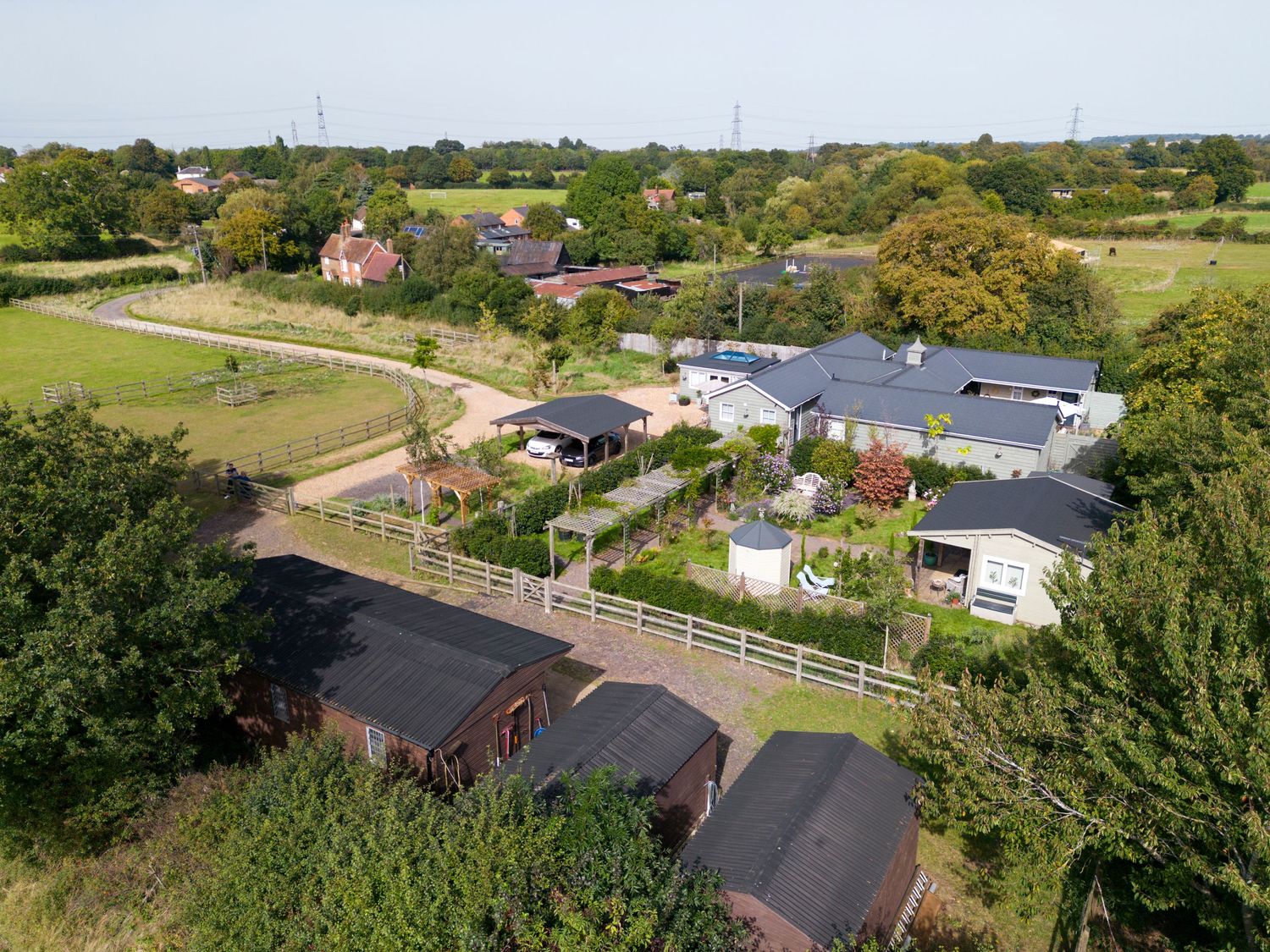 Aerial drone photograph of a countryside property showing multiple buildings, landscaped grounds, paddocks and surrounding rural landscape.