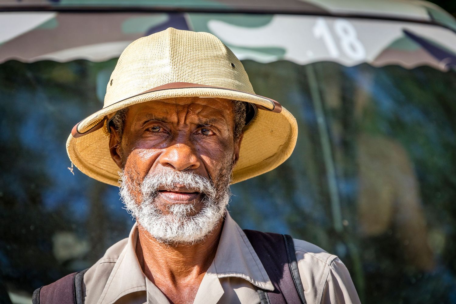 Portrait of an elderly man with white beard wearing a tan hat outdoors.