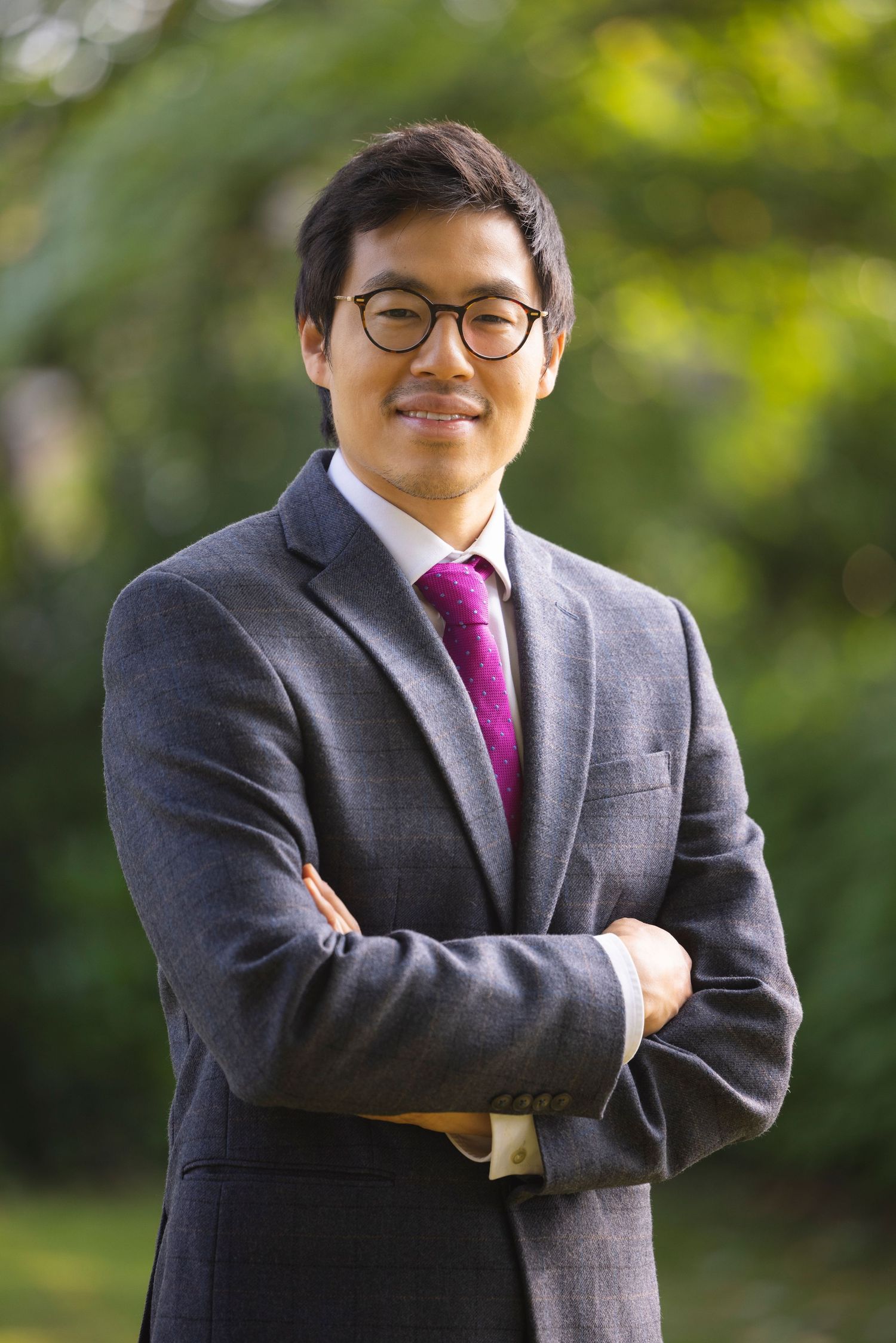 Professional businessman in a suit smiling outdoors during a corporate headshot and personal branding photography session.