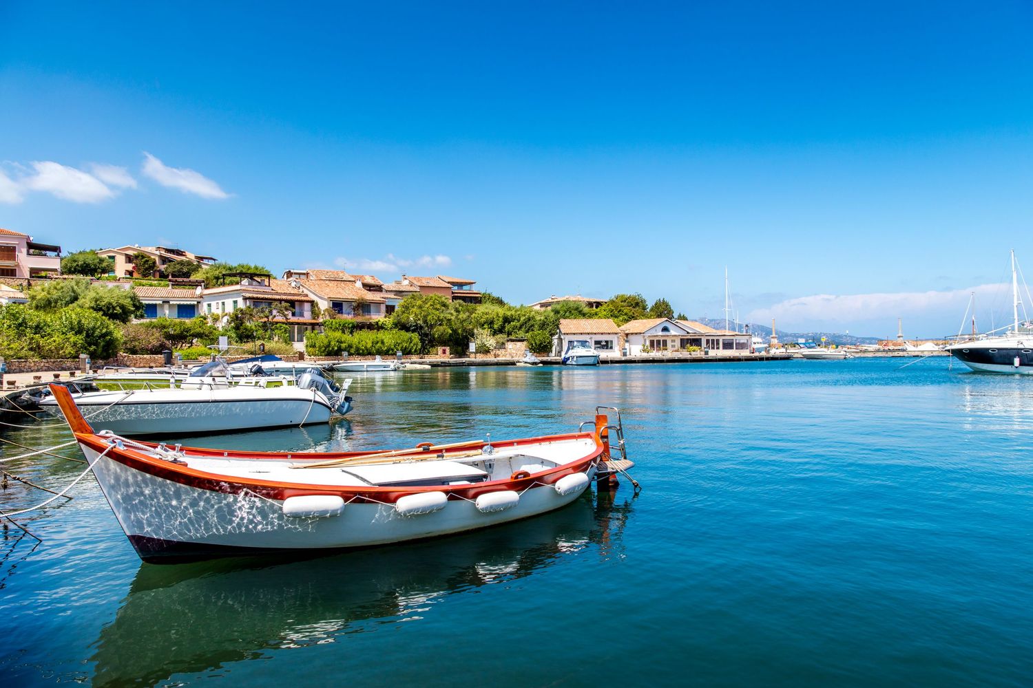 A traditional wooden boat moored in a calm marina in Sardinia, Italy.