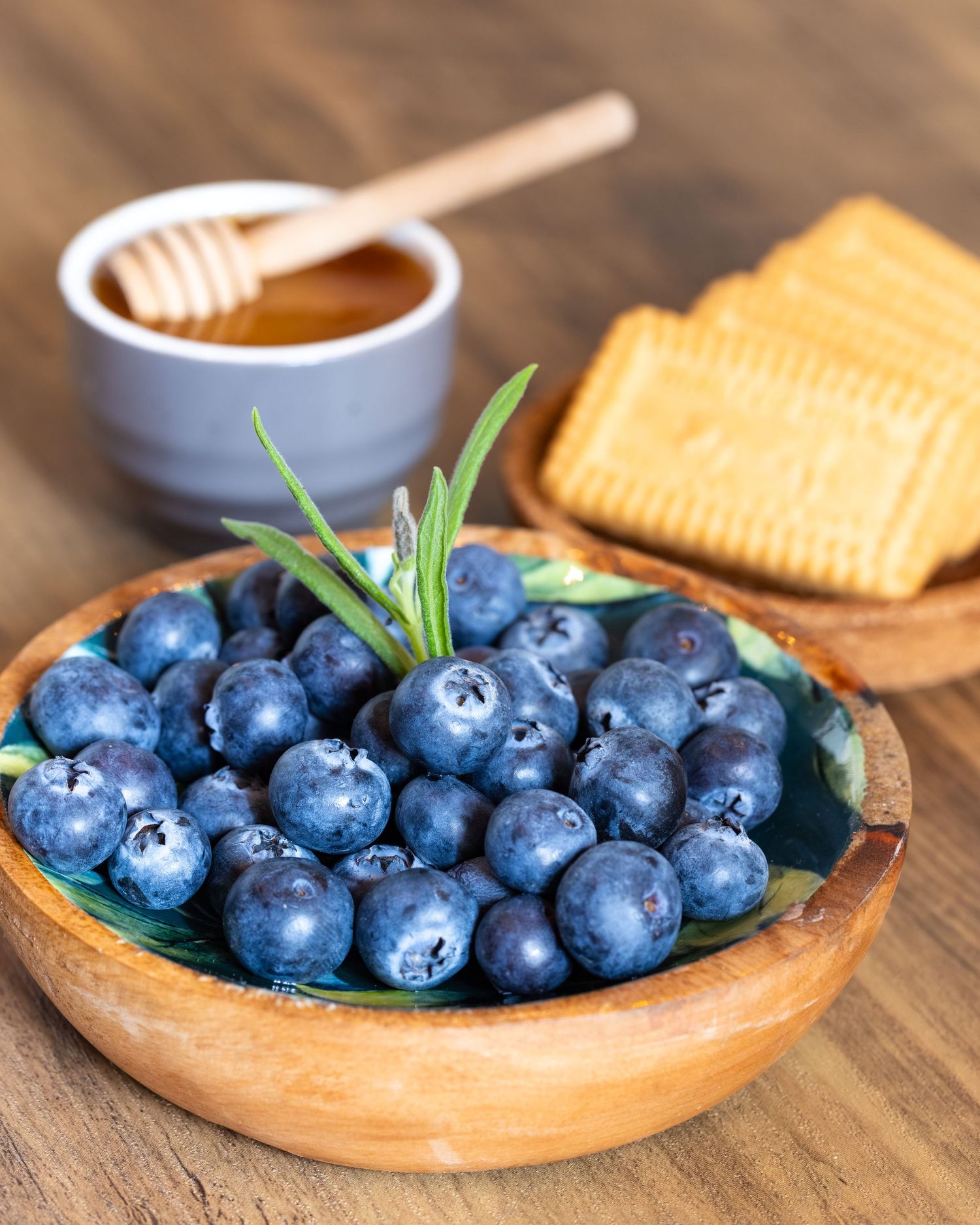 Styled spa detail in Bedfordshire with blueberries, rosemary, honey and crackers on wooden table, photographed during spa shoot.
