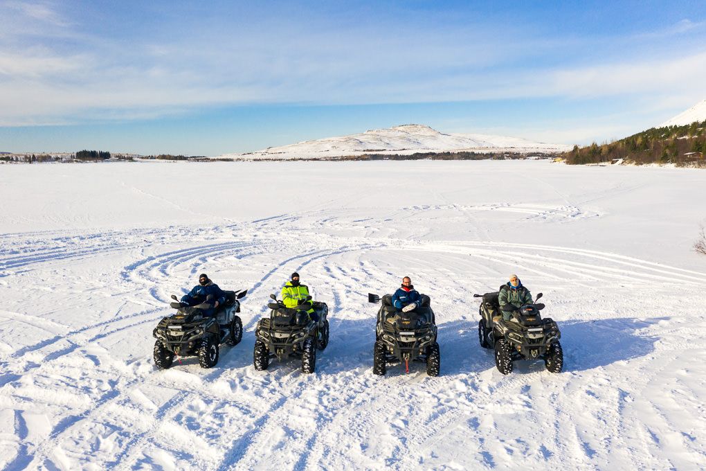 A drone photo of a group of ATVs parked in a line on a snowy winter landscape in Iceland.